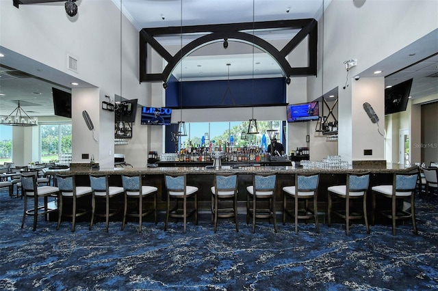 bar with beam ceiling, a high ceiling, and dark stone counters