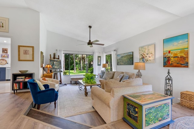 living room with light hardwood / wood-style floors, ceiling fan, and vaulted ceiling