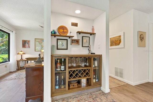 bar with light hardwood / wood-style floors and a textured ceiling