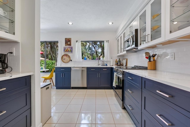 kitchen featuring light tile patterned floors, sink, backsplash, white cabinetry, and appliances with stainless steel finishes