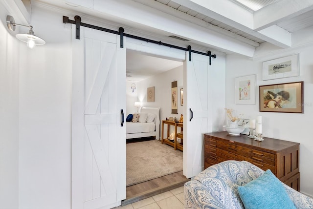 bedroom featuring beamed ceiling, a barn door, and light tile patterned floors