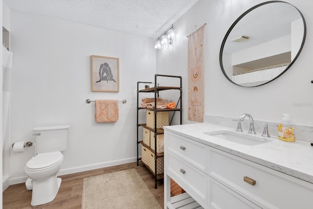 bathroom with vanity, hardwood / wood-style flooring, a textured ceiling, and toilet