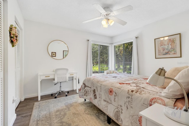 bedroom with a textured ceiling, wood-type flooring, and ceiling fan