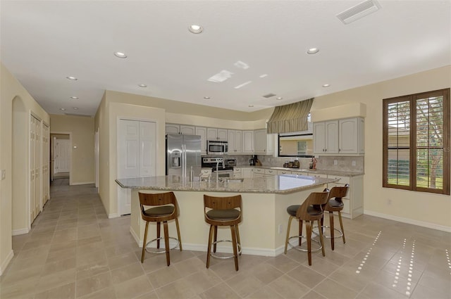 kitchen with appliances with stainless steel finishes, decorative backsplash, and an island with sink