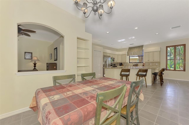 dining area featuring built in shelves, ceiling fan with notable chandelier, and light tile patterned floors