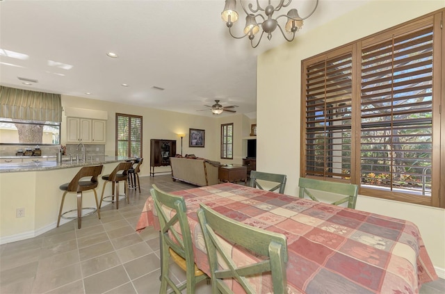 dining area with sink, ceiling fan with notable chandelier, and light tile patterned floors