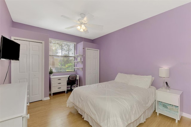 bedroom with light hardwood / wood-style floors, two closets, and ceiling fan