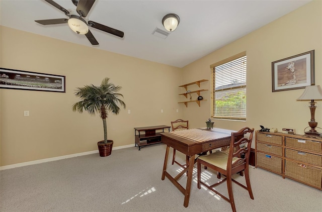 dining space with ceiling fan and light colored carpet