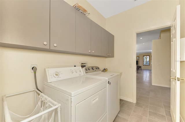 clothes washing area featuring cabinets, light tile patterned flooring, and washing machine and dryer