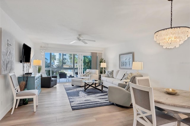 living room with ceiling fan with notable chandelier and light hardwood / wood-style floors