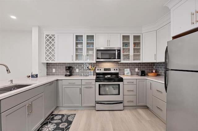 kitchen featuring appliances with stainless steel finishes, gray cabinets, light hardwood / wood-style flooring, and sink