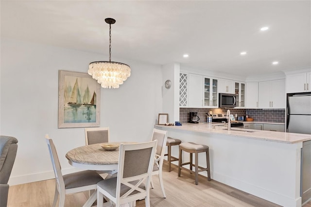 dining area featuring light hardwood / wood-style flooring, a notable chandelier, and sink