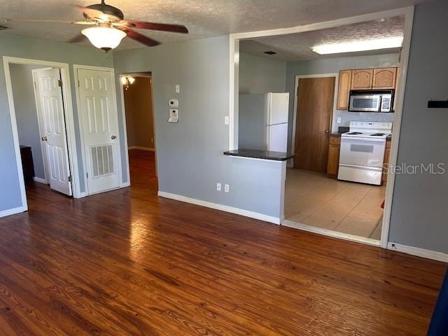 kitchen featuring white appliances, ceiling fan, a textured ceiling, and dark hardwood / wood-style floors