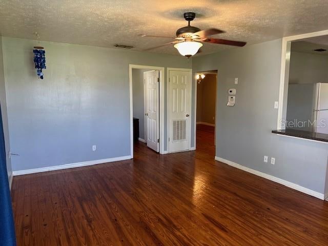 spare room featuring dark wood-type flooring, ceiling fan, and a textured ceiling