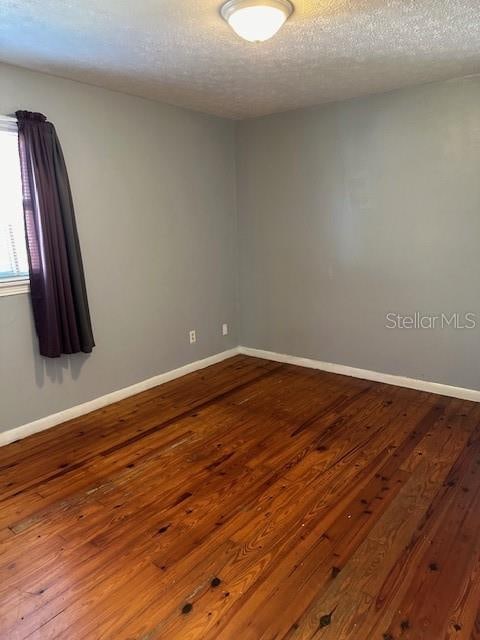 empty room with hardwood / wood-style flooring and a textured ceiling