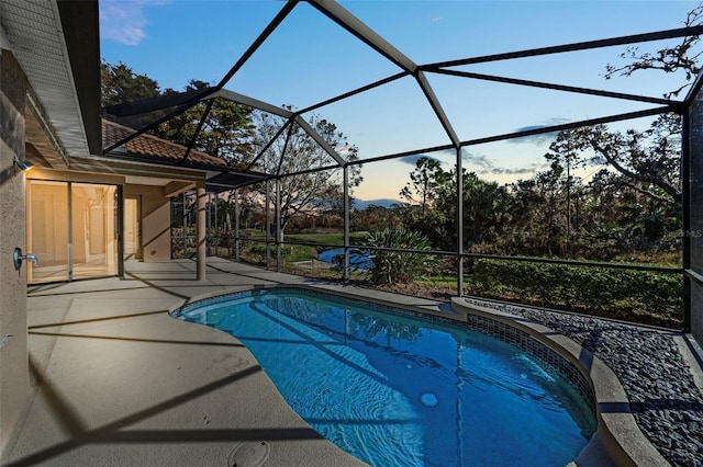 pool at dusk with a patio and glass enclosure