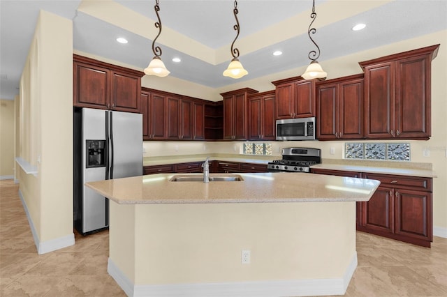 kitchen with light stone countertops, sink, hanging light fixtures, an island with sink, and appliances with stainless steel finishes