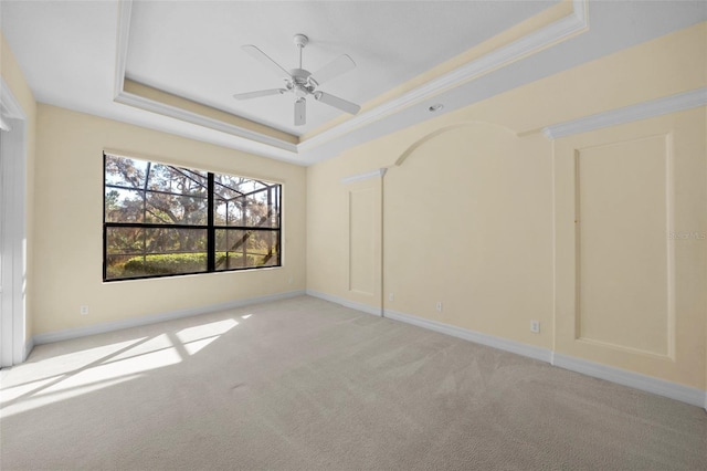 spare room with a tray ceiling, ceiling fan, and light colored carpet