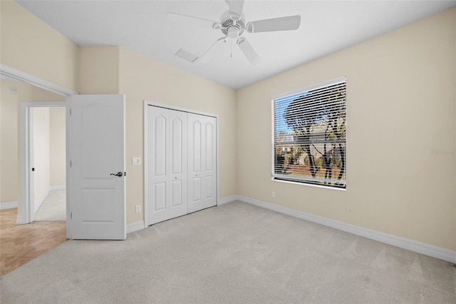 unfurnished bedroom featuring ceiling fan, light colored carpet, and a closet