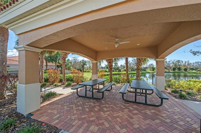 view of patio with ceiling fan and a water view