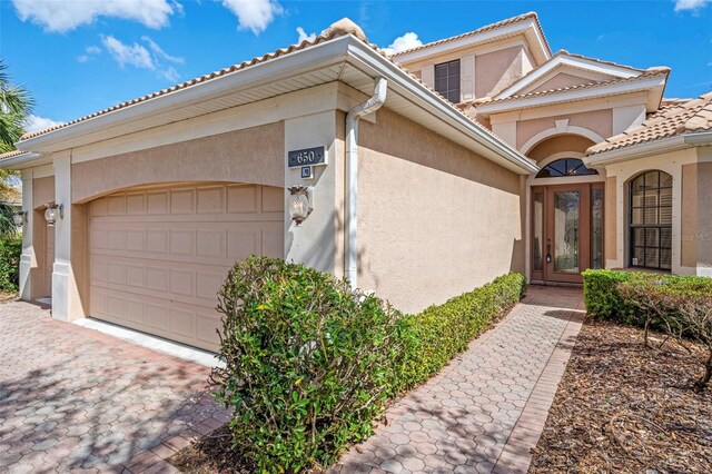 view of front of home with an attached garage, decorative driveway, stucco siding, and a tile roof