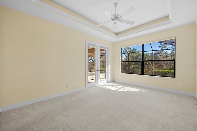 spare room with baseboards, ceiling fan, a tray ceiling, french doors, and carpet flooring