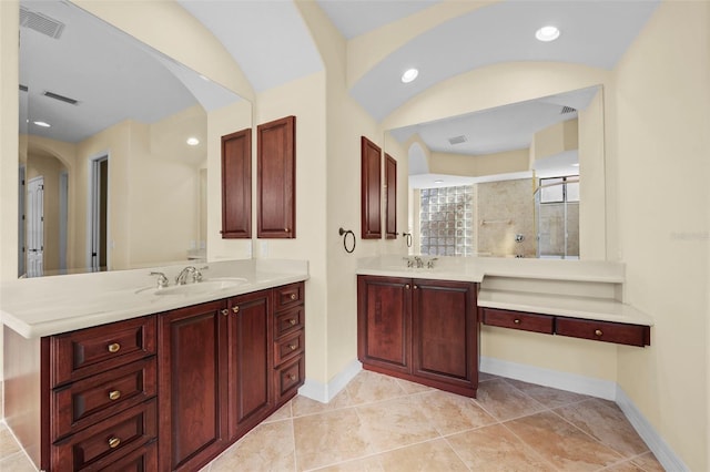 bathroom featuring a sink, baseboards, tiled shower, and visible vents