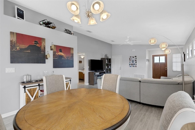 dining room with lofted ceiling, light hardwood / wood-style flooring, and ceiling fan with notable chandelier