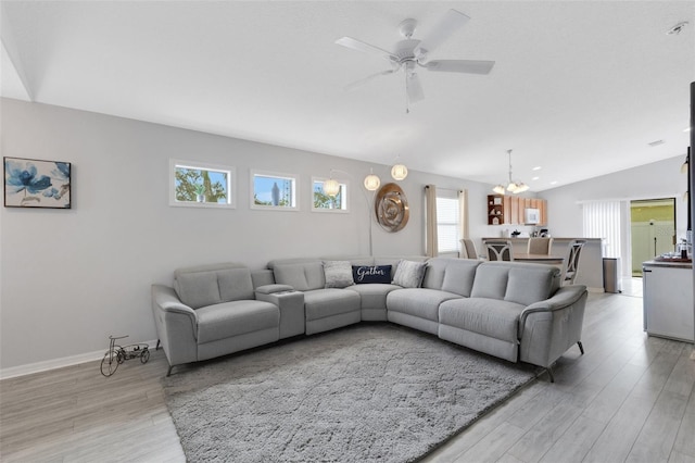 living room with lofted ceiling, light wood-type flooring, and ceiling fan with notable chandelier