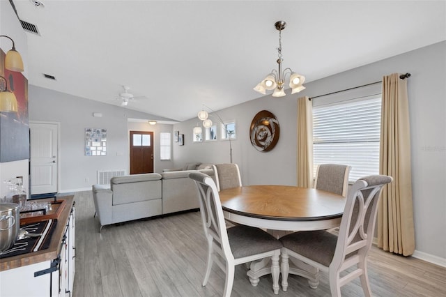 dining space with light hardwood / wood-style floors, lofted ceiling, and ceiling fan with notable chandelier