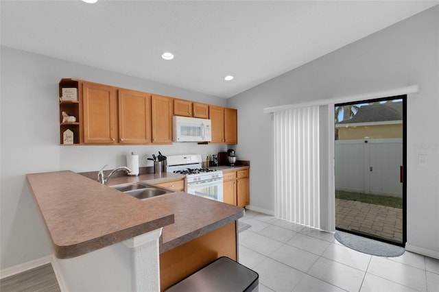 kitchen with lofted ceiling, kitchen peninsula, a kitchen breakfast bar, sink, and white appliances