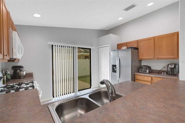 kitchen with black range with gas stovetop, lofted ceiling, stainless steel fridge with ice dispenser, and sink