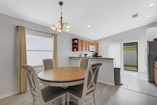 dining space featuring vaulted ceiling, light wood-type flooring, and an inviting chandelier