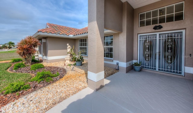 property entrance with a patio area, a tile roof, and stucco siding