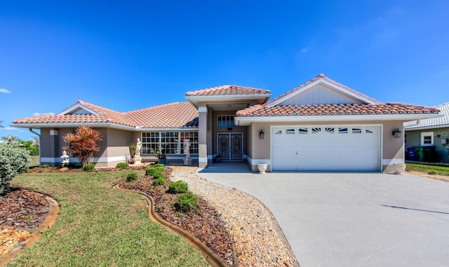 mediterranean / spanish house with a garage, driveway, and a tile roof