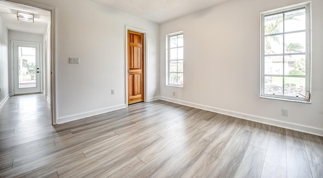 spare room with plenty of natural light, light wood-style flooring, and baseboards