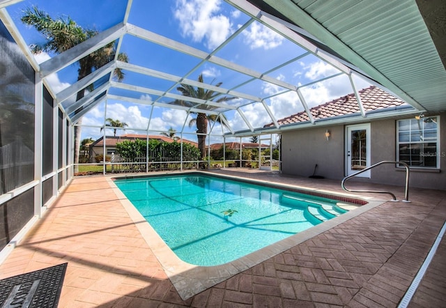 outdoor pool featuring glass enclosure and a patio