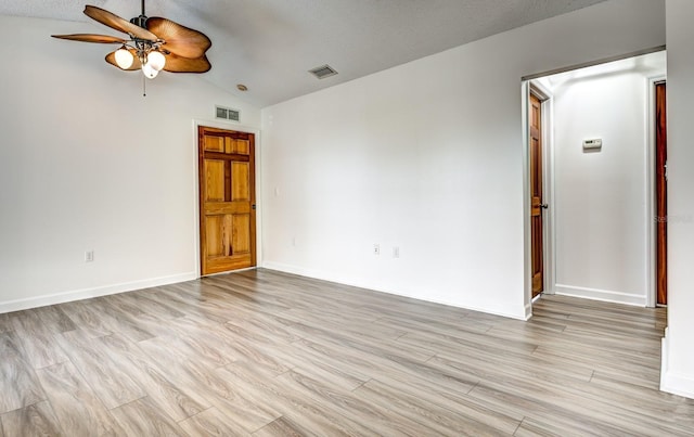 empty room with visible vents, vaulted ceiling, and light wood-style flooring