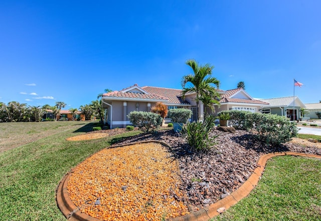 view of front of house with an attached garage, a tile roof, a front lawn, and stucco siding