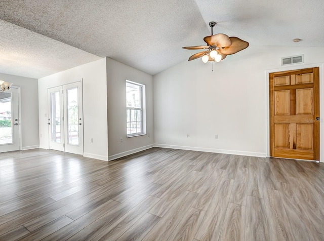 unfurnished living room with lofted ceiling, light wood finished floors, visible vents, and a wealth of natural light