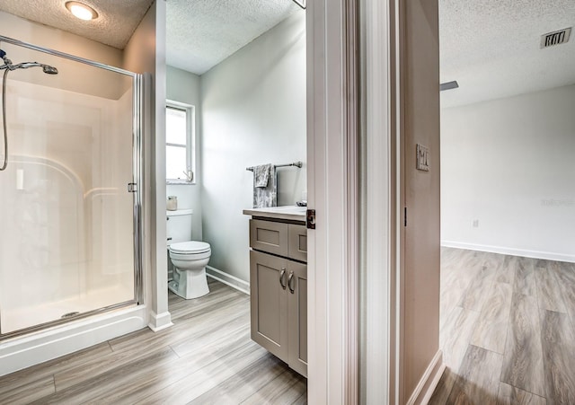 bathroom with visible vents, toilet, a stall shower, vanity, and wood finished floors