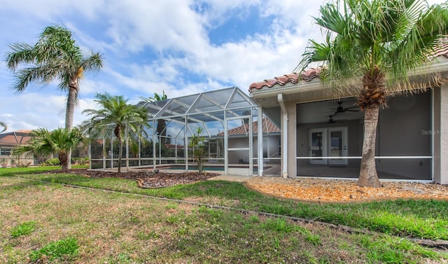 view of yard with an outdoor pool, glass enclosure, and ceiling fan