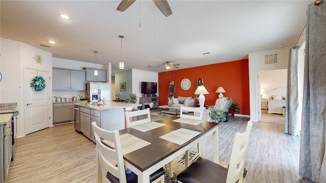 dining area featuring sink, ceiling fan, and light hardwood / wood-style flooring