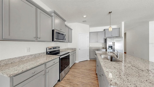 3718 Mossy Limb Ct, Palmetto, FL 34221 - kitchen with appliances with stainless steel finishes, a sink, gray cabinetry, light wood-style floors, and light stone counters