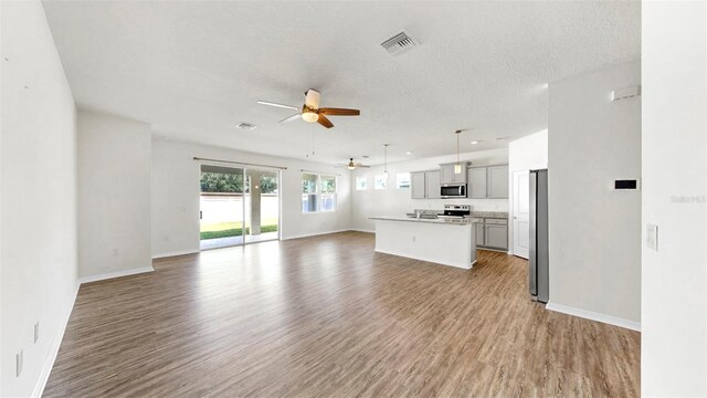 3718 Mossy Limb Ct, Palmetto, FL 34221 - unfurnished living room featuring a ceiling fan, wood finished floors, baseboards, and a textured ceiling