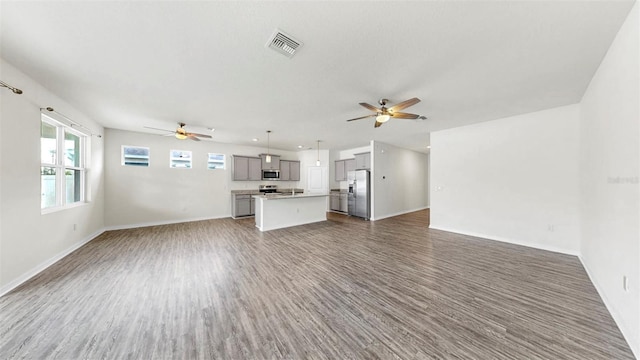 3718 Mossy Limb Ct, Palmetto, FL 34221 - unfurnished living room featuring a ceiling fan, wood finished floors, and healthy amount of natural light