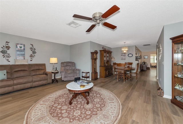 living room featuring light hardwood / wood-style floors, a textured ceiling, and ceiling fan with notable chandelier