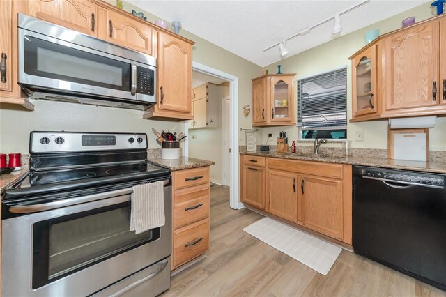 kitchen featuring track lighting, light hardwood / wood-style flooring, stainless steel appliances, sink, and stone counters