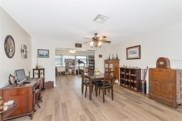 dining area with a textured ceiling, light wood-type flooring, and ceiling fan