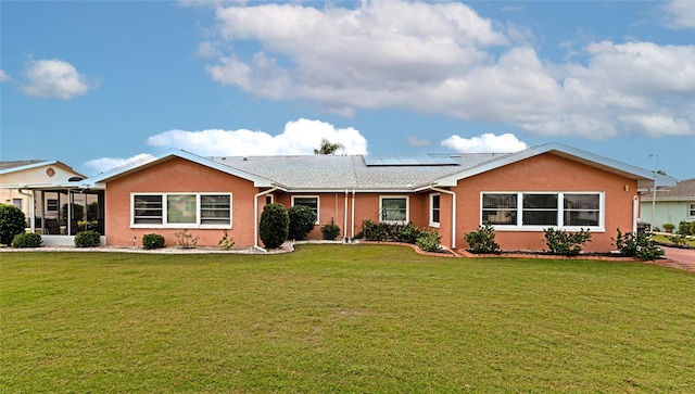 ranch-style home with solar panels, a front lawn, and a sunroom